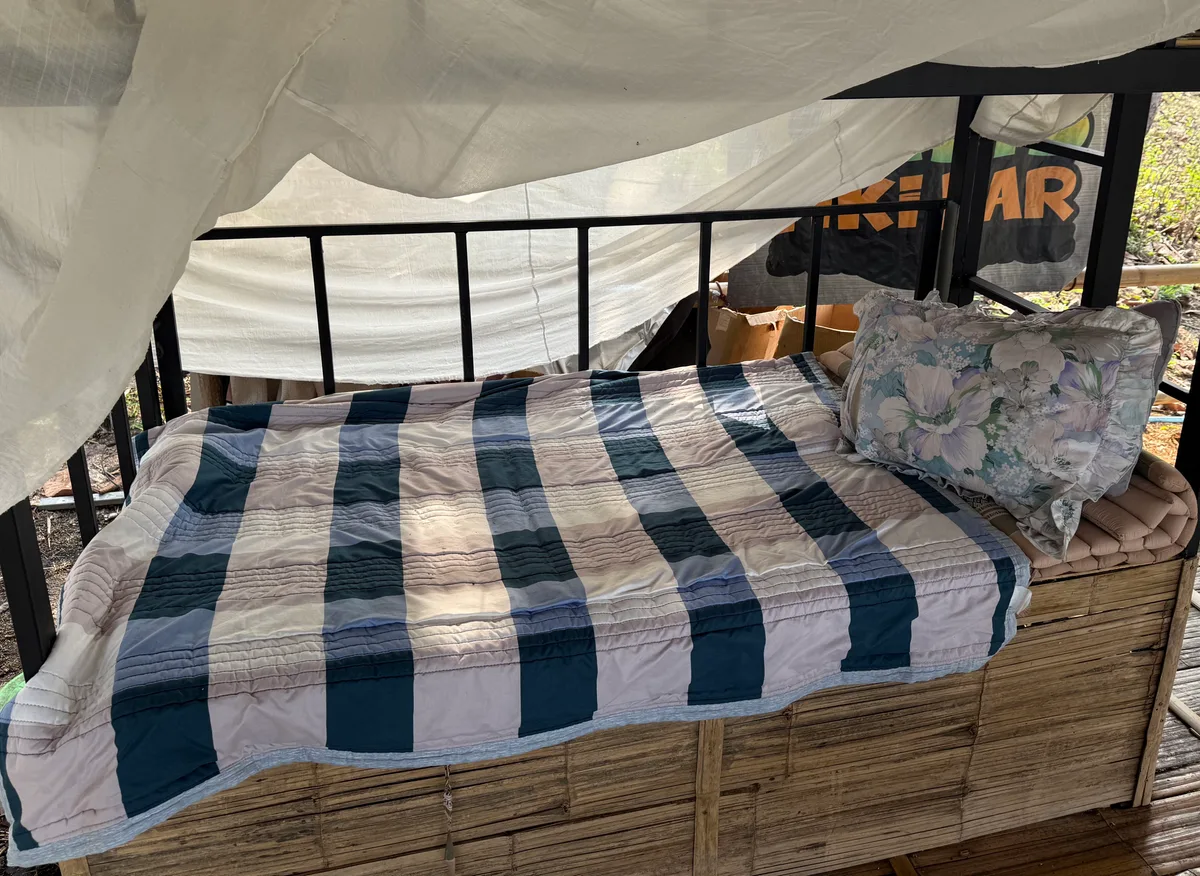 An individual bunk bed with a blue-and-white quilt, pillow and mosquito netting at Bungalows & Bunks in Pai.